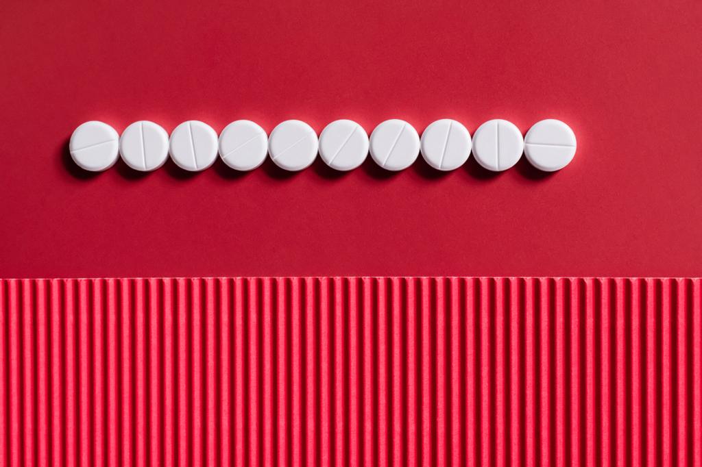 Ansicht der Reihe mit weißen Pillen in runder Form auf karminrotem und strukturiertem Hintergrund - Foto, Bild