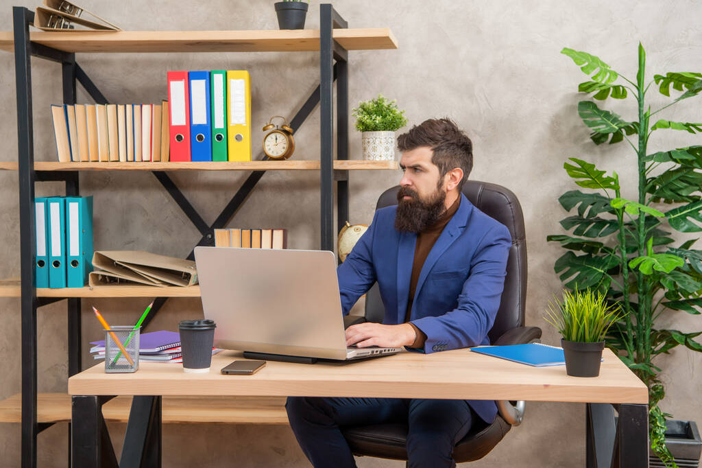 自信のある髭のボスがオフィスのノートパソコンでオンラインで勉強ビジネス教育 - 写真・画像