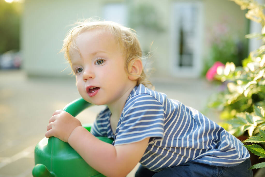 Bonito menino criança regando flores no jardim no dia de verão. Criança usando regador no dia ensolarado. Mamãs ajudante pouco. - Foto, Imagem