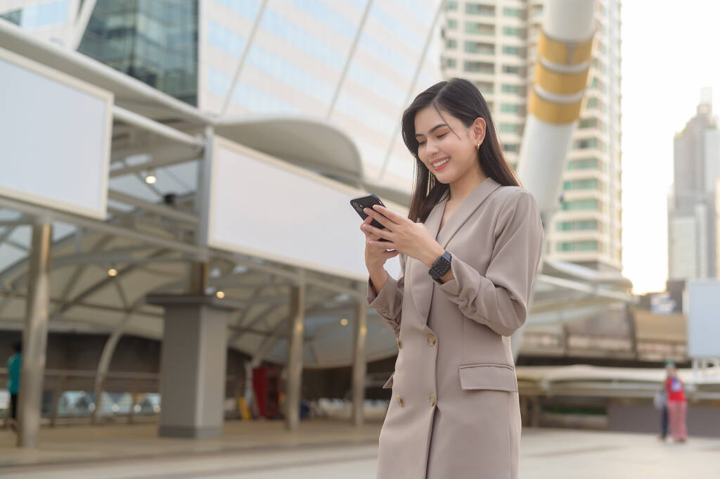 Молодая красивая деловая женщина использует смартфон в современном городе, бизнес-технологии, городской стиль жизни  - Фото, изображение