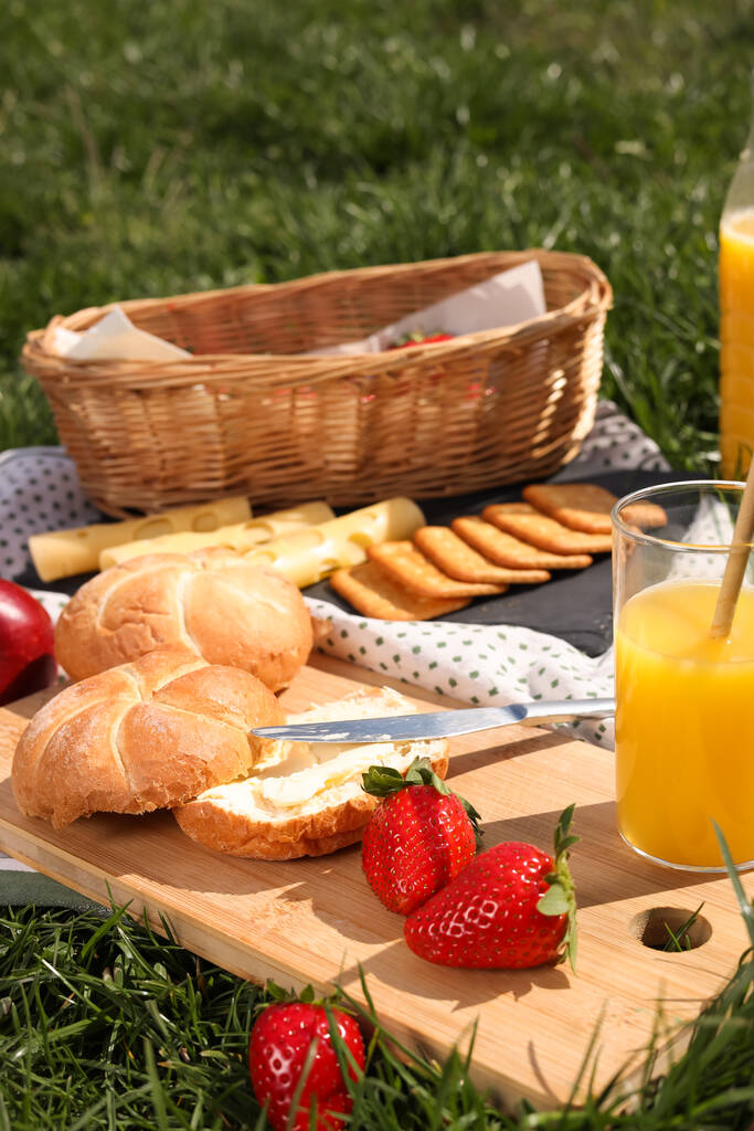 Ковдра з соком і закусками для пікніка на зеленій траві
 - Фото, зображення