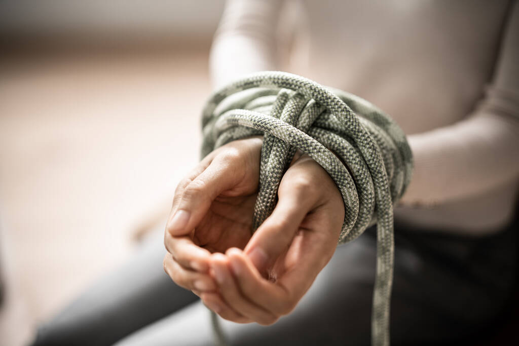 Slavernij slachtoffer en gijzelaar vastgebonden door touw. Geweld en misdaad - Foto, afbeelding
