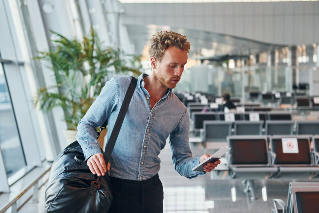 Молодой человек в формальной одежде находится в современном аэропорту. Концепция отпуска. - Фото, изображение