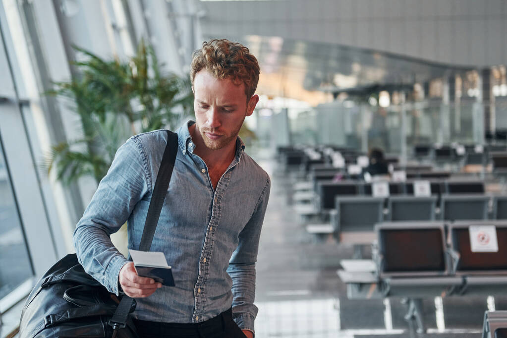 Junger Mann in formeller Kleidung steht auf einem modernen Flughafen. Konzeption von Urlaub. - Foto, Bild