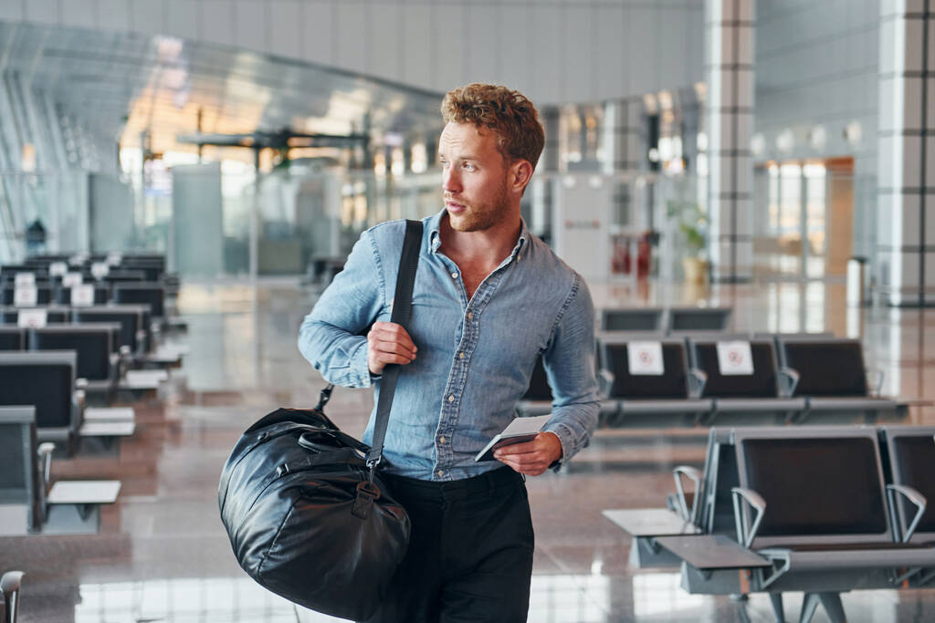 Hombre joven en ropa formal está en el aeropuerto moderno. Concepción de vacaciones. - Foto, Imagen
