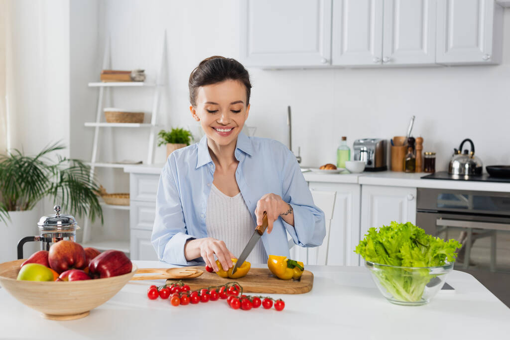 femme gaie préparer le petit déjeuner à partir de légumes frais dans la cuisine - Photo, image