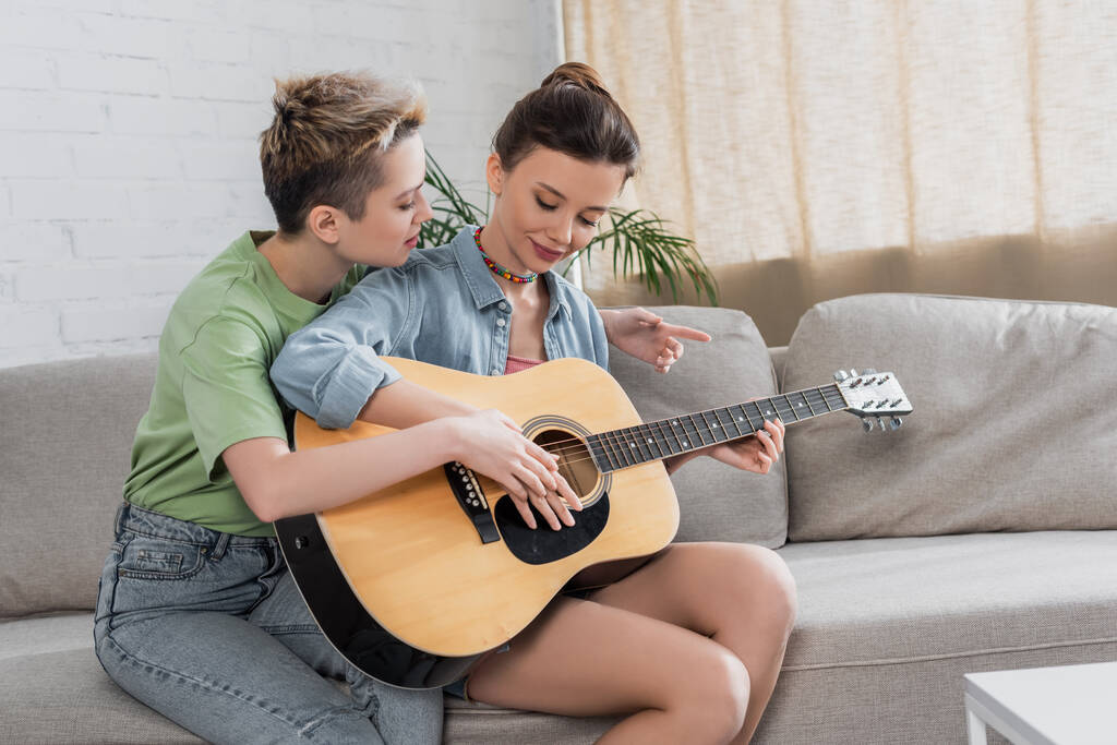 fiatal zenész tanít pansexual partner gitározni otthon - Fotó, kép
