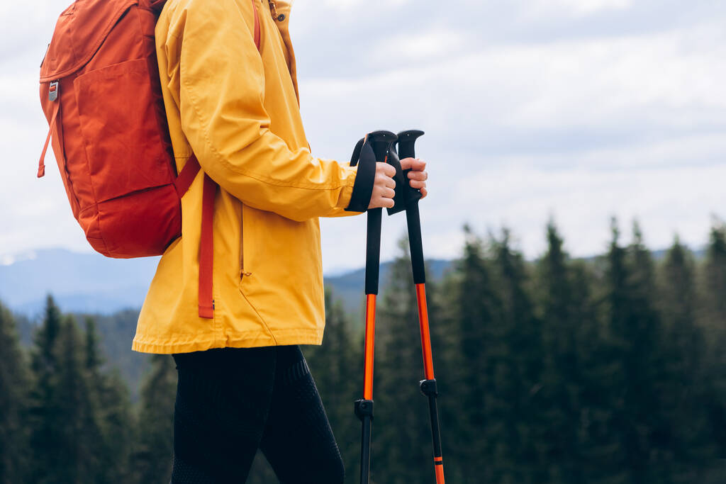 Close up Hiker with trekking poles goes against mountain landscape. Hiking and travel concept - Foto, Bild