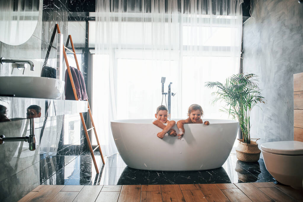 Dos niños divirtiéndose y lavándose en el baño en casa. Posando para una cámara. - Foto, Imagen