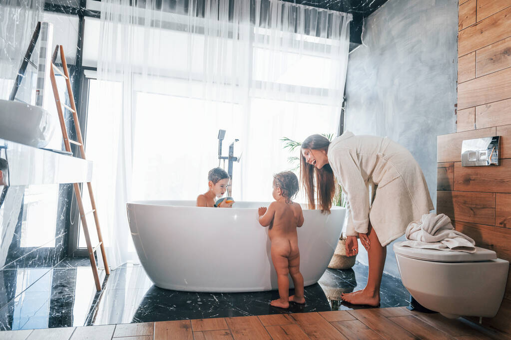 After washing. Young mother helps her son and daughter. - 写真・画像
