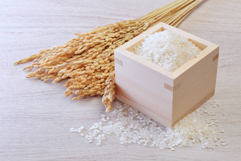 Tahta fincanda beyaz pirinç ve ahşap arka planda çeltik pirinç kulakları.. - Fotoğraf, Görsel