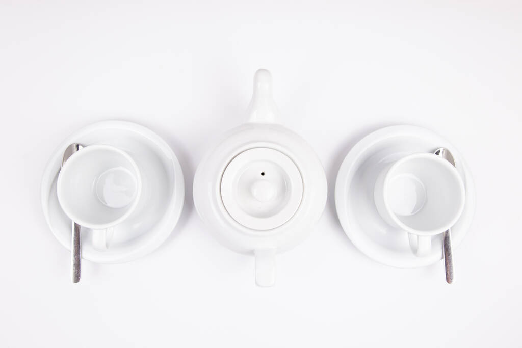 una teiera di porcellana bianca e una tazza sul piattino per caffè o tè vuoto - Foto, immagini