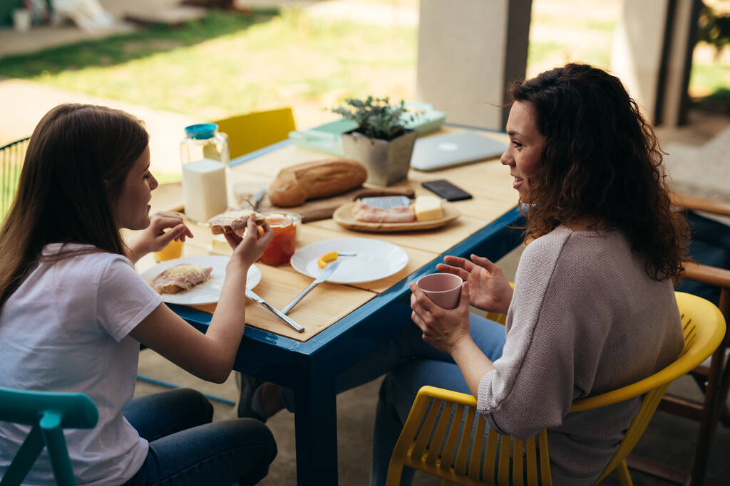 young girl talks with her mom while breakfast together outdoor - Fotografie, Obrázek