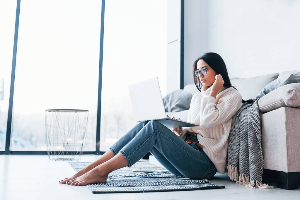 Giovane bella donna in occhiali seduta a casa da sola con il computer portatile. - Foto, immagini