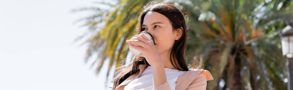 low angle view of brunette woman drinking coffee outdoors, banner - Valokuva, kuva