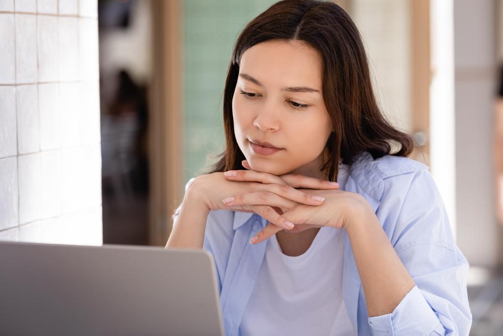 mujer con las manos cerradas mirando el ordenador portátil al aire libre - Foto, imagen