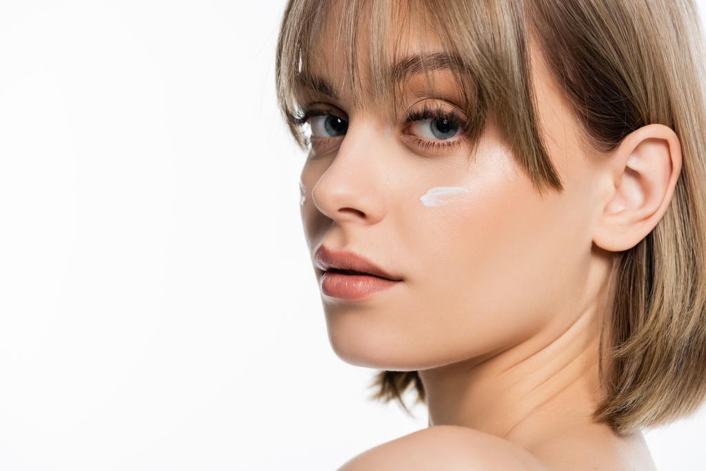 woman with bangs and cream on cheeks looking at camera isolated on white - Photo, image