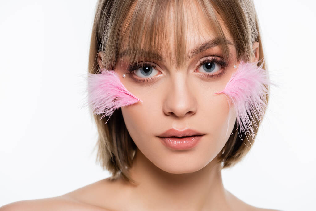 young woman with decorative elements in makeup and pink feathers on cheeks isolated on white - Fotografie, Obrázek