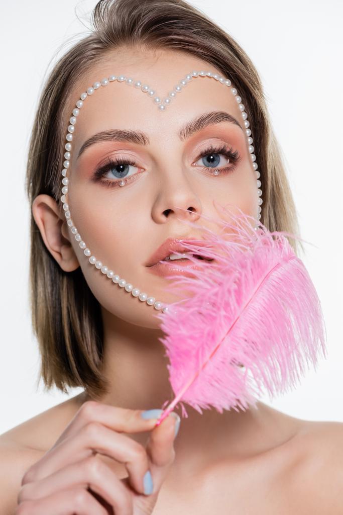 pretty woman with creative heart shape beads on face holding pink feather isolated on white  - Foto, immagini