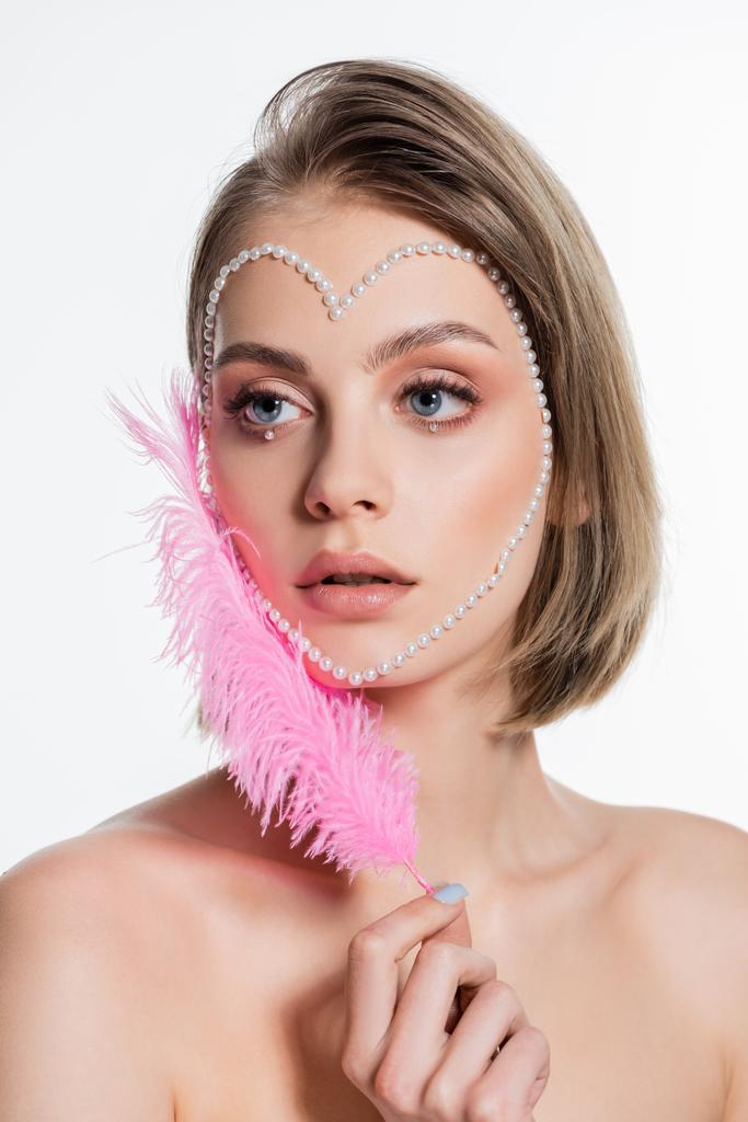 young woman with creative heart shape beads on face holding pink feather isolated on white  - Valokuva, kuva