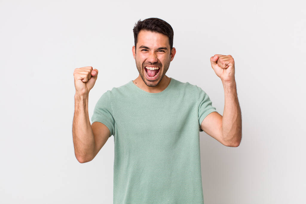молодий красивий іспаномовний чоловік відчуває себе щасливим, позитивним і успішним, святкуючи перемогу, досягнення або удачу
 - Фото, зображення