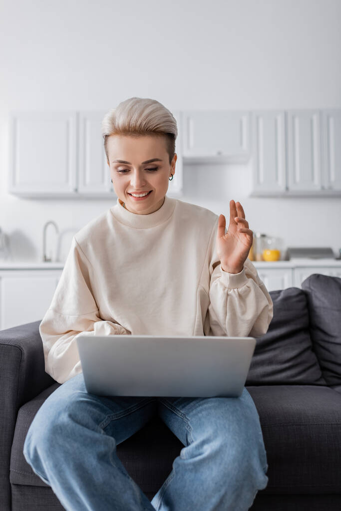 mulher sorrindo mão acenando durante chamada de vídeo no laptop em casa - Foto, Imagem