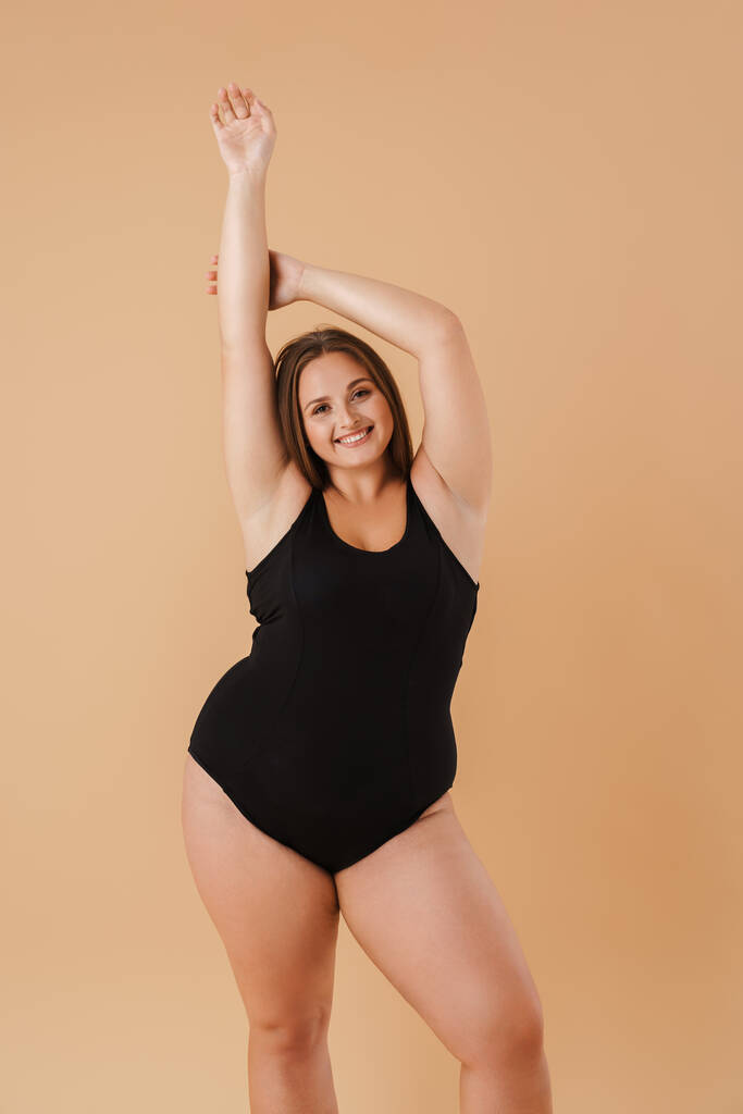 Young woman wearing swimsuit smiling and looking at camera isolated over beige background - Foto, Imagem