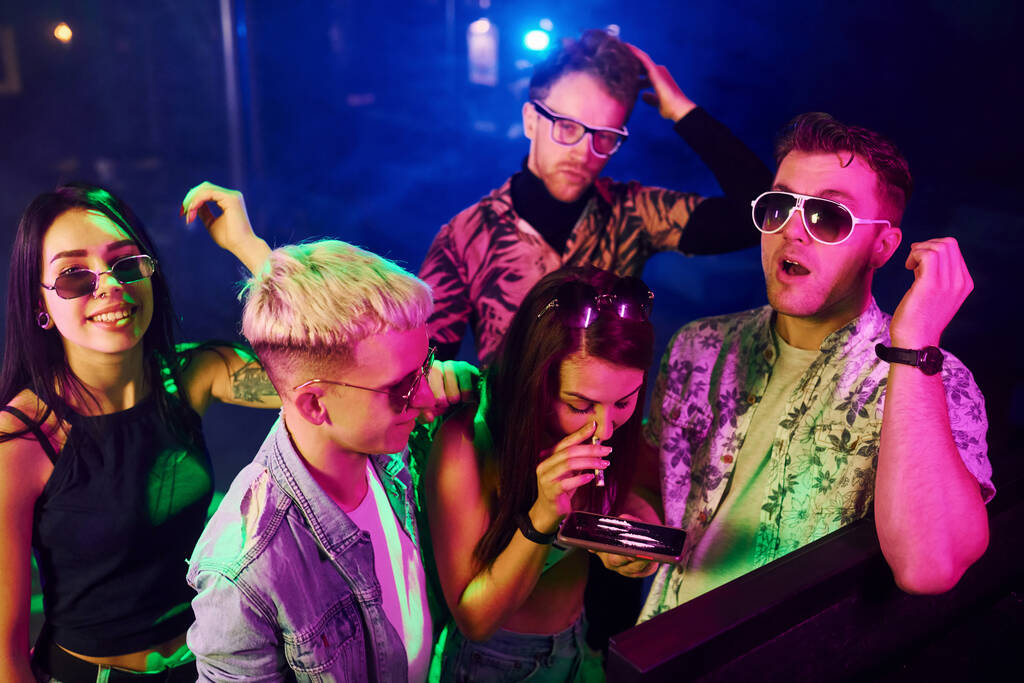 Jongeren snuiven drugs in nachtclub met kleurrijke laserlichten. - Foto, afbeelding