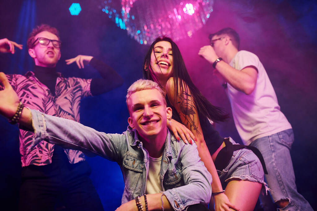 Going crazy and posing for the camera together. Young people is having fun in night club with colorful laser lights. - Photo, Image