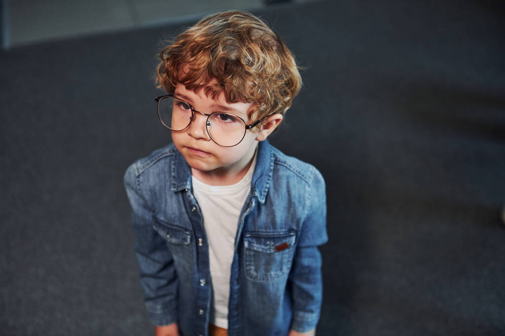 Portret uroczego dziecka w okularach stojącego w pomieszczeniu. - Zdjęcie, obraz