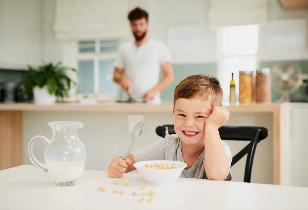 Je těžké nebýt spokojený se snídaní. Postřelen rozkošný malý chlapec se snídaní se svým otcem v pozadí doma. - Fotografie, Obrázek