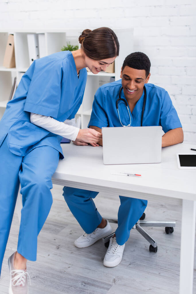 Positive multiethnic vet doctors looking at laptop in clinic  - Фото, изображение
