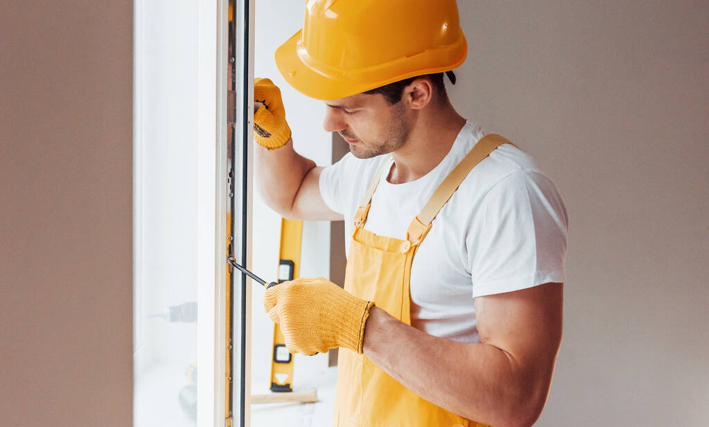 Handyman in yellow uniform installs new window. House renovation conception. - Fotó, kép