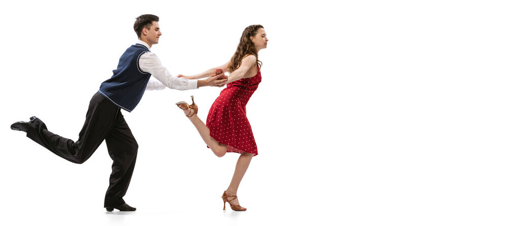 Быстрый шаг. Девушка и стильный мужчина в винтажных нарядах в стиле ретро танцуют на белом фоне. Вечные традиции, 60-е, 70-е, стиль и искусство американской моды - Фото, изображение