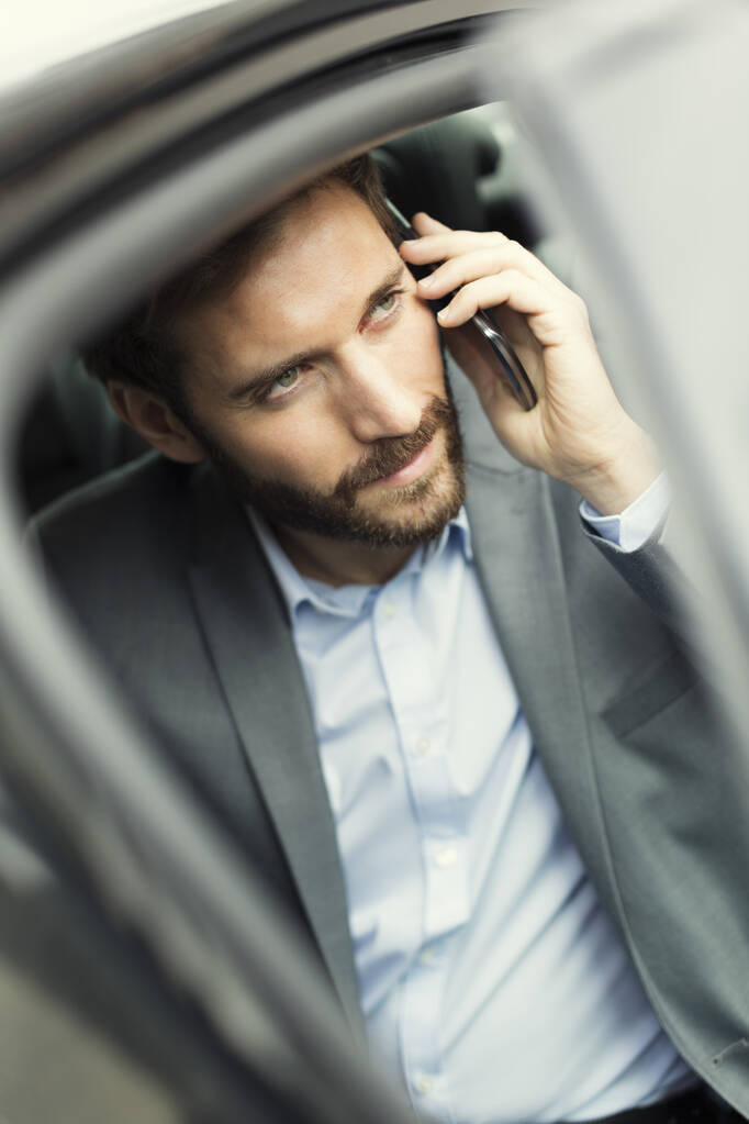 Homme d'affaires occasionnel sur téléphone portable à l'arrière de la voiture
 - Photo, image