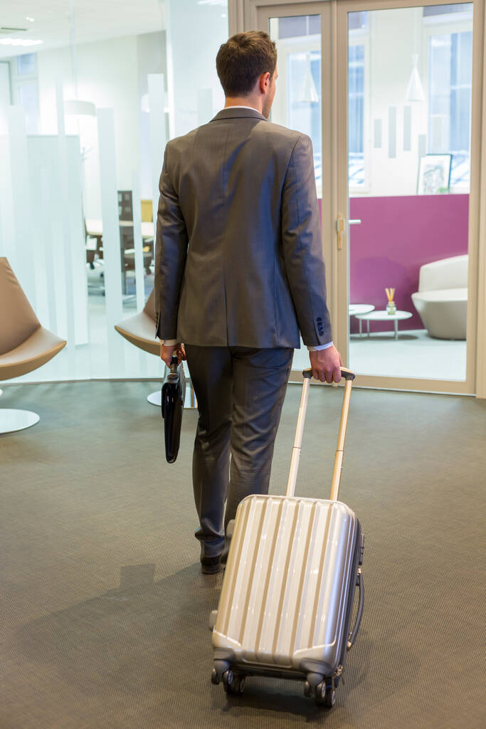 Επιχειρηματίας με τις αποσκευές του στο γραφείο εισόδου. - Φωτογραφία, εικόνα