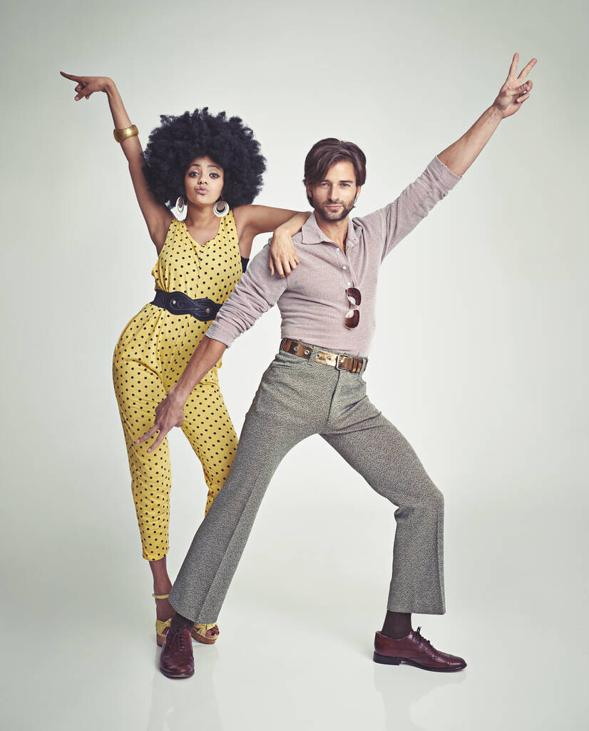 Vamos a bailar. Una atractiva pareja joven de pie juntos en ropa retro de los años 70. - Foto, Imagen