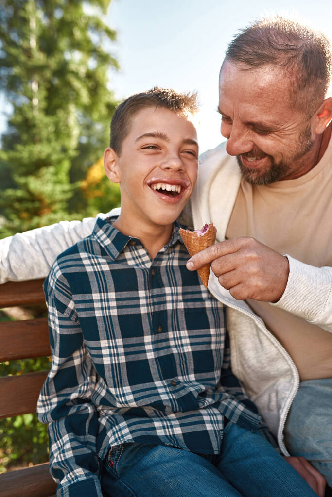 Caucasian father feed ice cream joyful teenage son - Photo, Image