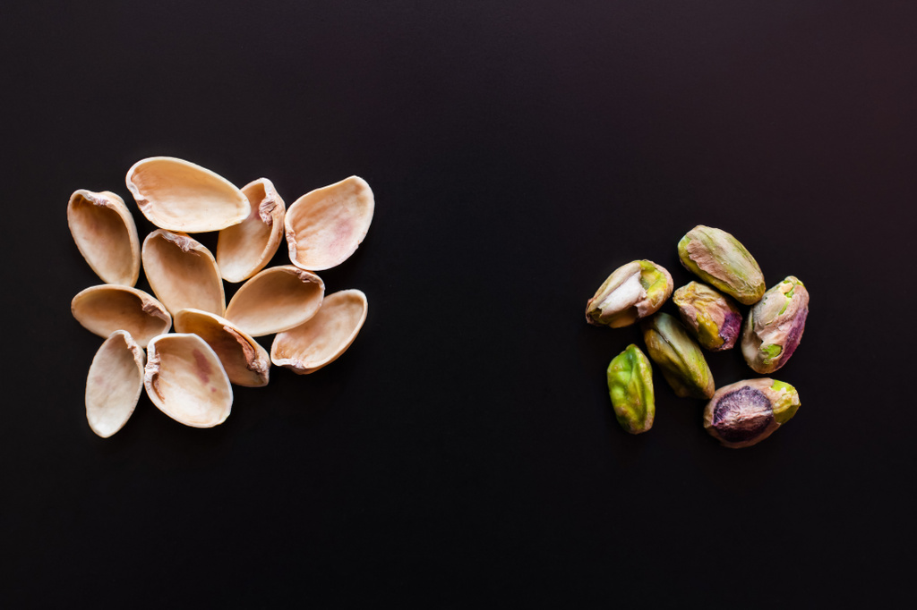 top view of nutshells near pistachios isolated on black  - Foto, Imagem