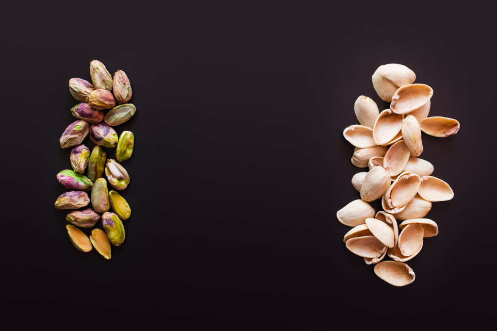 top view of nutshells near tasty pistachios isolated on black  - Zdjęcie, obraz
