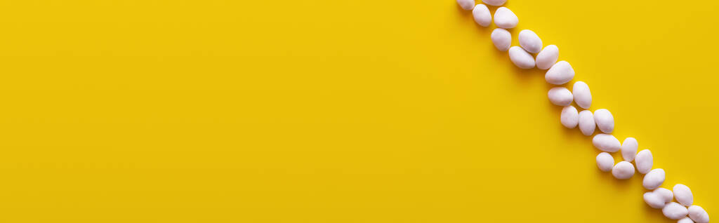 Ansicht der Reihe mit geschälten Pinienkernen auf gelbem Hintergrund, Banner - Foto, Bild