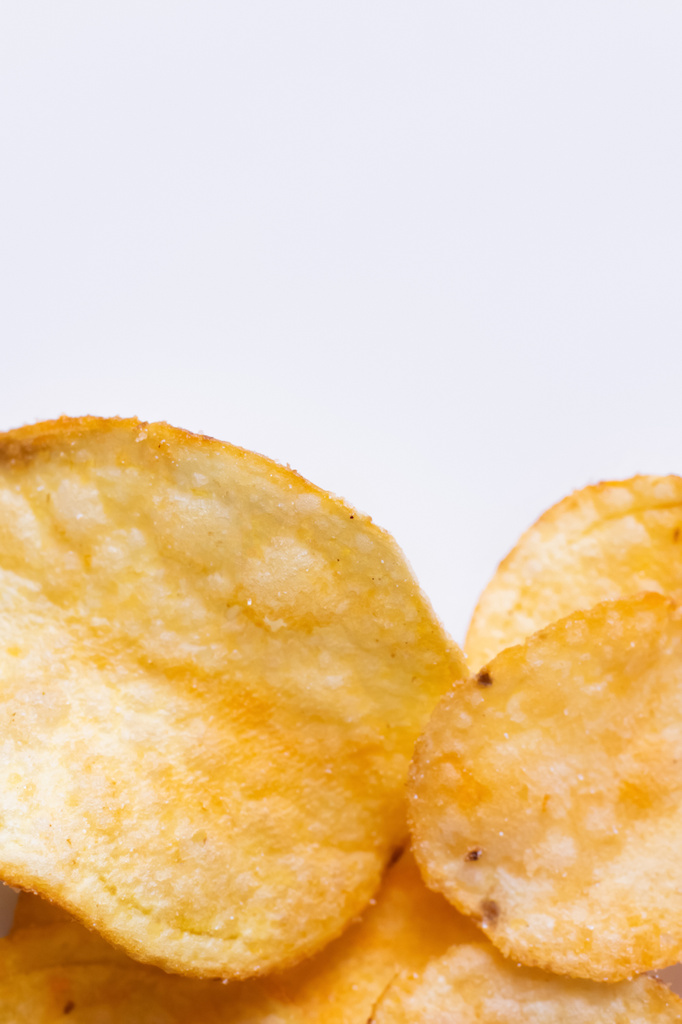 закрыть вид на вкусные и соленые картофельные чипсы на белом - Фото, изображение