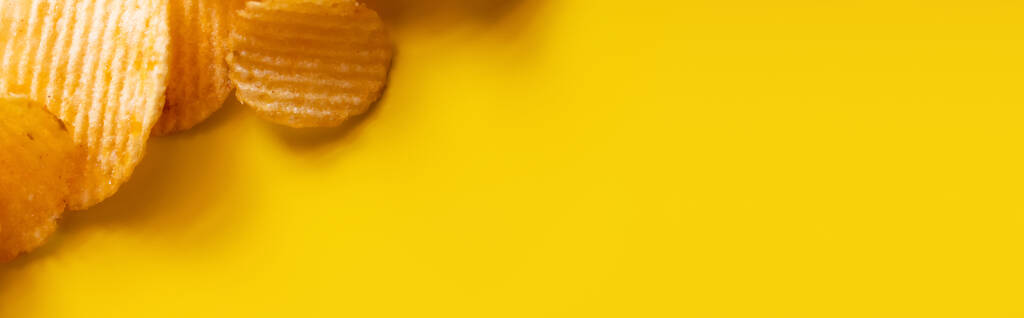 top view of wavy and salty potato chips on yellow, banner - Photo, image