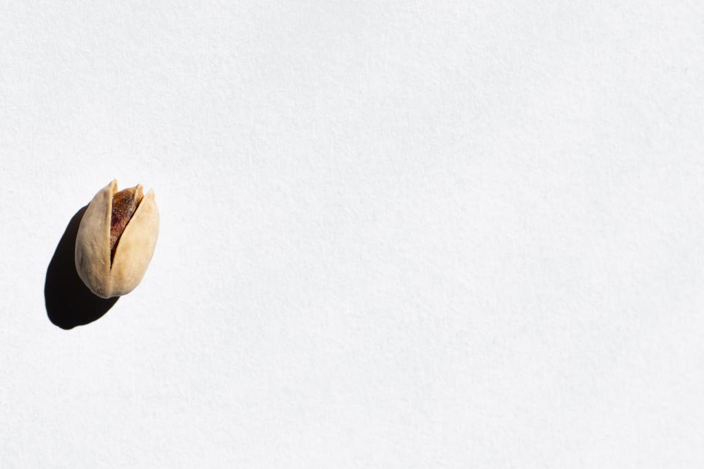 top view of single cracked pistachio nut on white background - Zdjęcie, obraz