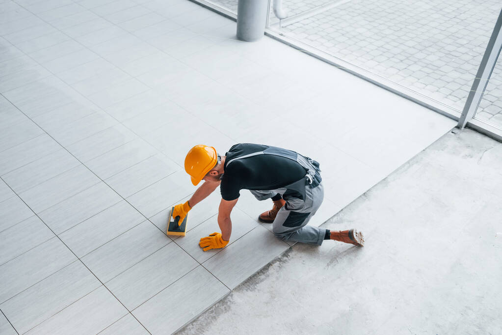Top view of man in grey uniform that installing plate indoors in modern big office at daytime. - Fotoğraf, Görsel