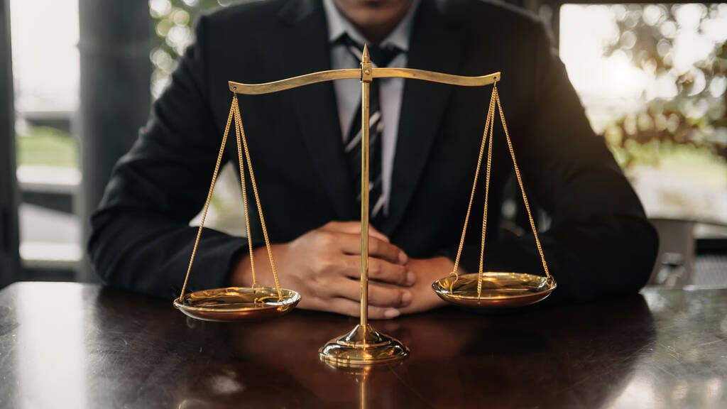 Mężczyzna prawnika w biurze z mosiądzu skali na drewnianym stole. pojęcie prawa i sprawiedliwości w świetle poranka - Zdjęcie, obraz