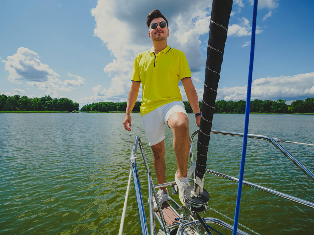 handsome young black hair person wear casual clothes standing on a sailboat bow and looking at front in sunny summer day - Foto, immagini