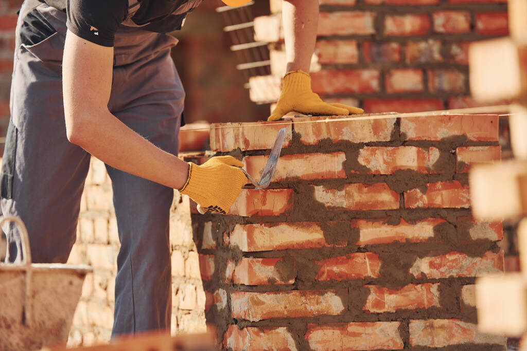 Busy with brick wall. Construction worker in uniform and safety equipment have job on building. - Φωτογραφία, εικόνα