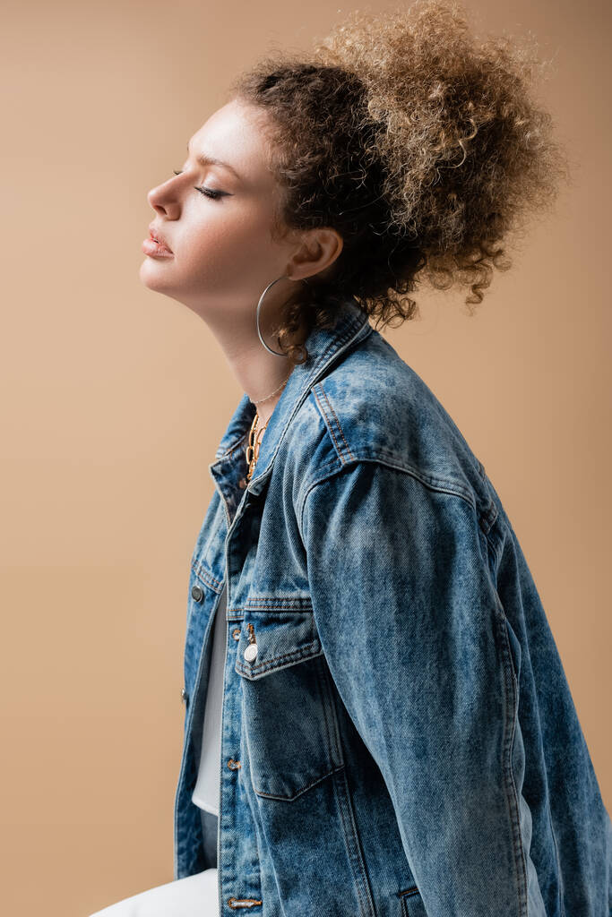 Young model in denim jacket and accessories isolated on beige  - Photo, Image