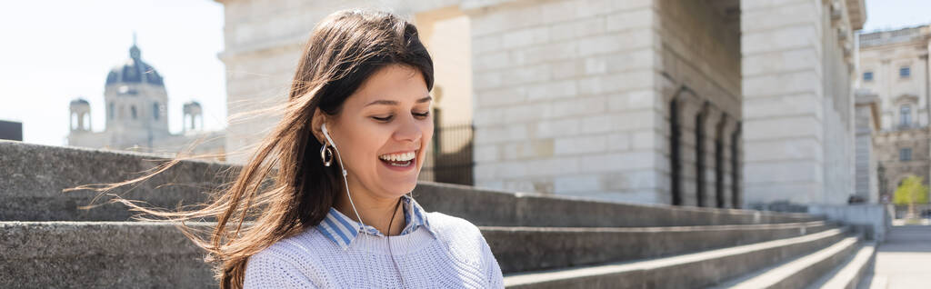 fröhliche Frau, die Musik in kabelgebundenen Kopfhörern hört und lächelt, Banner - Foto, Bild